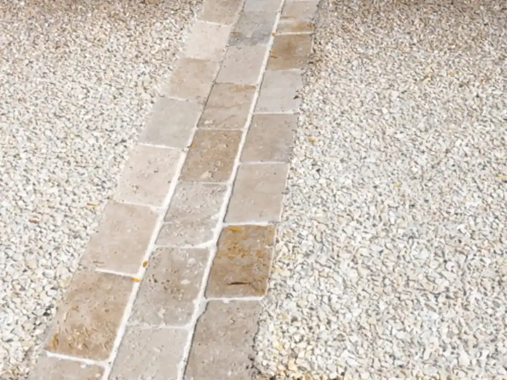 Detaliu de pavaj exterior care combină o alee din dale de piatră cu zone laterale din beton dezactivat (piatră spălată).