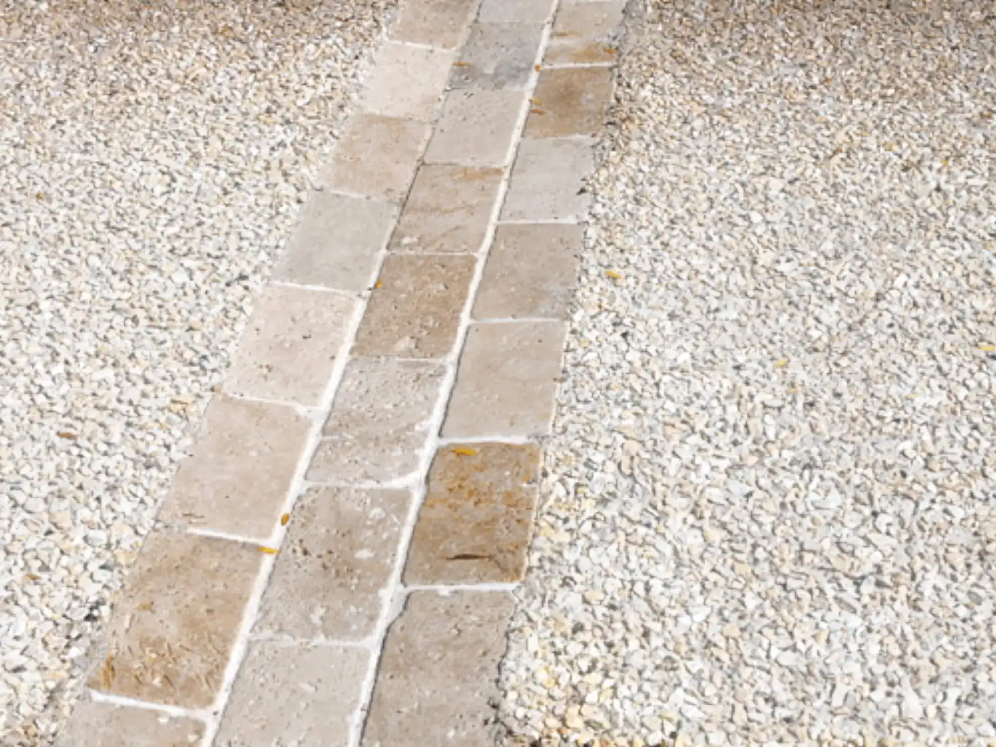 Detaliu de pavaj exterior care combină o alee din dale de piatră cu zone laterale din beton dezactivat (piatră spălată).